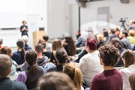 A speaker giving a lecture in a busy lecture theatre.