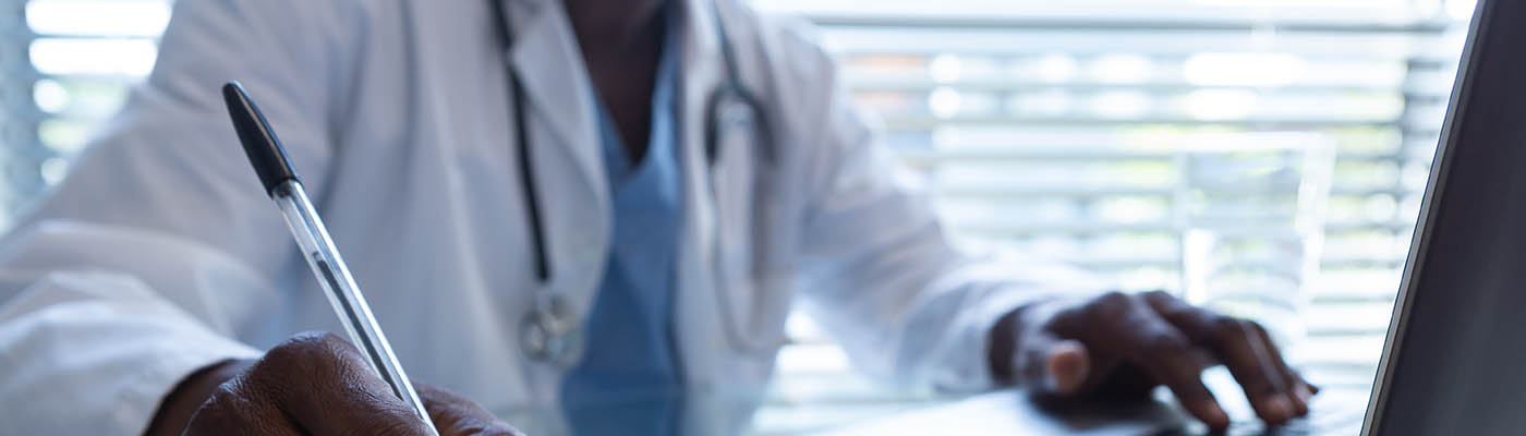 A clinician working at a computer in a hospital.